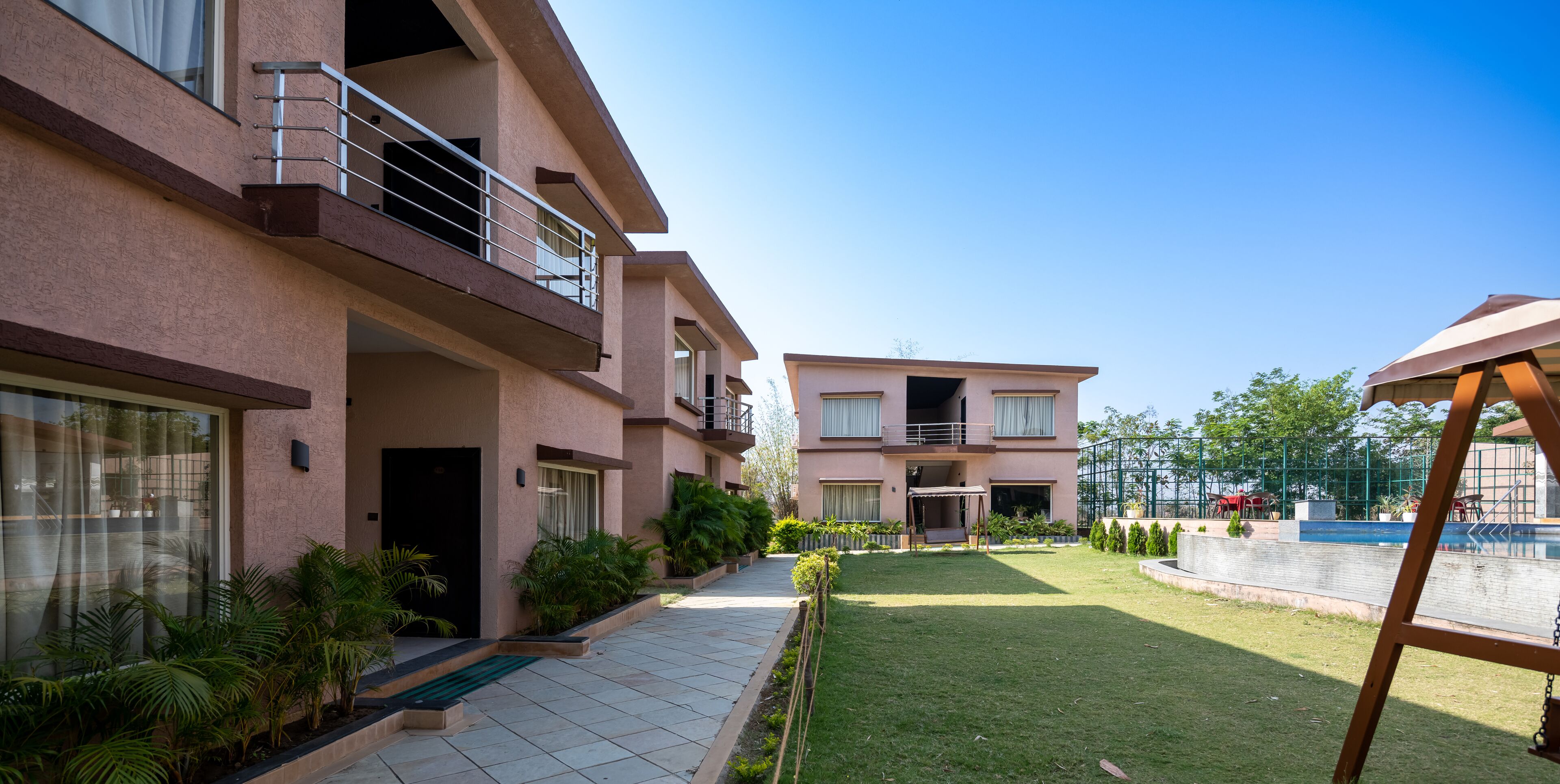 A multi-story residential building with balconies, a swimming pool, and a well-maintained lawn.
