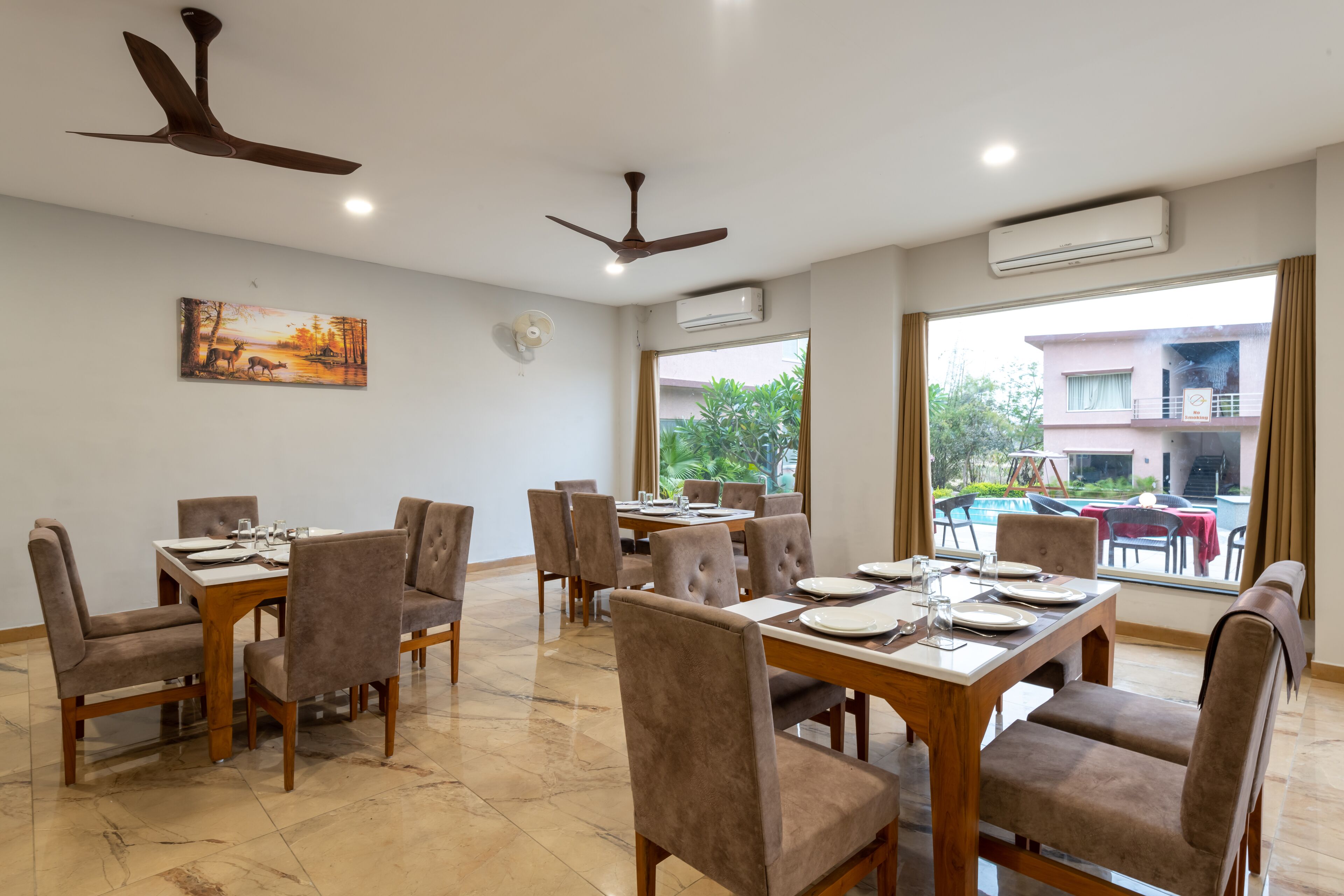 A dining area with multiple tables and chairs, ceiling fans, and an air conditioning unit.