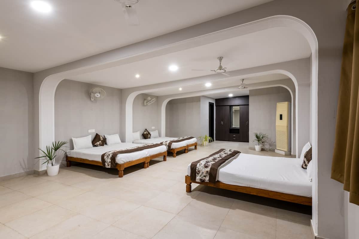 Quarto de hotel com quatro camas de solteiro, um ventilador de teto e um espelho grande.