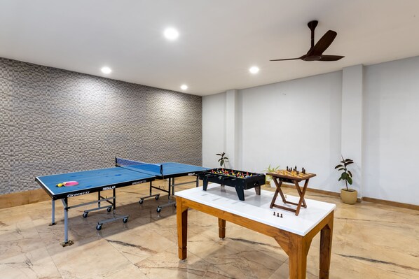 Una habitación con mesa de ping pong, mesa de fútbolín y mesa de ajedrez.