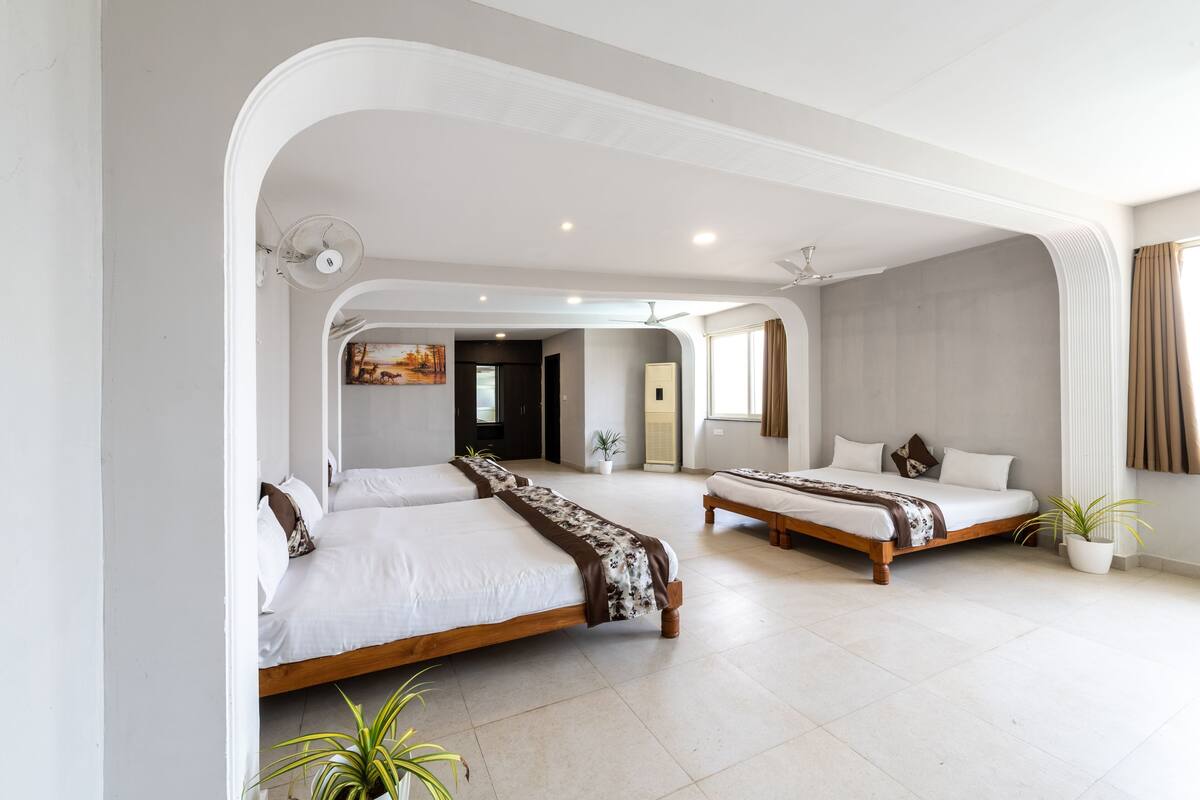 Quarto de hotel moderno com duas camas, uma janela grande e vista para a cidade.