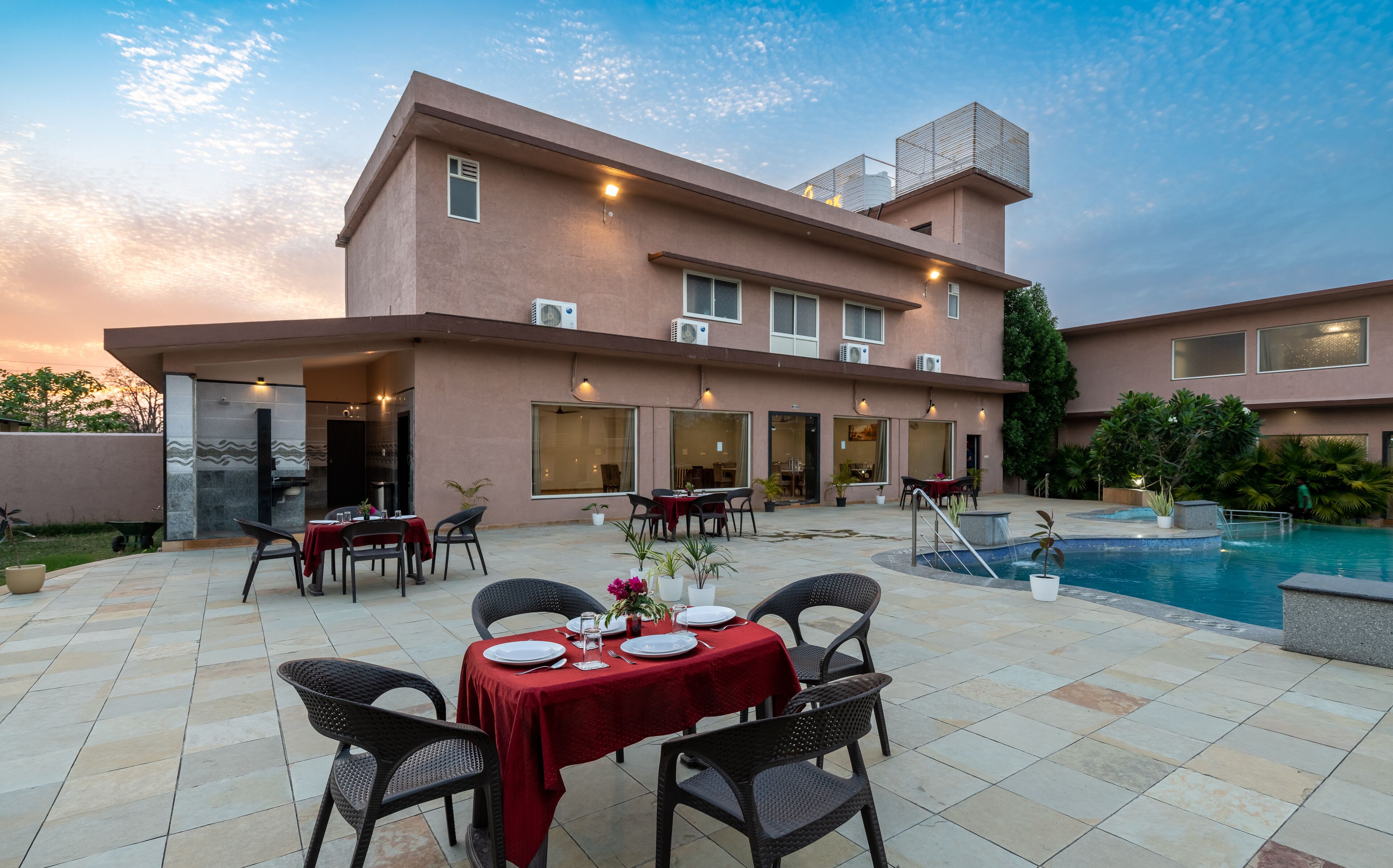 A hotel with outdoor dining and a swimming pool.