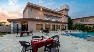 A hotel with outdoor dining and a swimming pool.