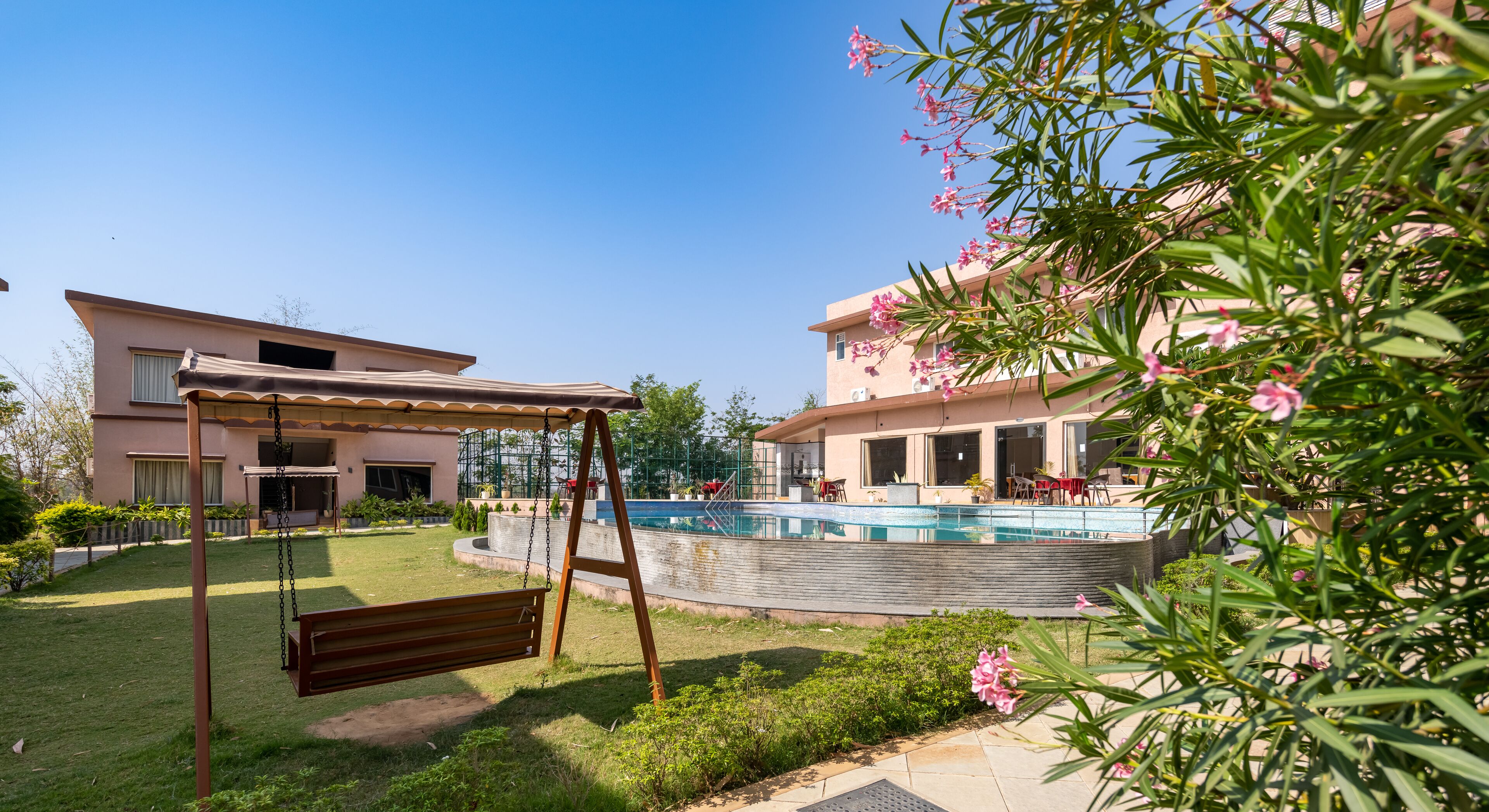 A residential building with a swimming pool, a swing set, and a covered patio area.