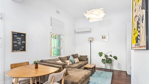 A modern living room with a dining area, a sofa set, a coffee table, and a blue rug. - Saltbush Cottage in fabulous South Fremantle. (South Fremantle)