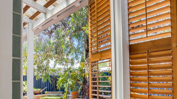 A bathroom with a glass shower enclosure, a bathtub, and wooden blinds on the windows. - Saltbush Cottage in fabulous South Fremantle. (South Fremantle)
