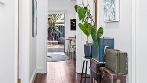 A hallway with a potted plant, a framed picture, and vintage suitcases. - Saltbush Cottage in fabulous South Fremantle. (South Fremantle)