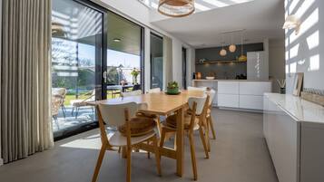 Een moderne keuken met witte kasten, een houten eettafel en uitzicht naar buiten.