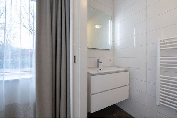 A modern bathroom with a white vanity, a mirror, and a towel rack.