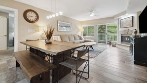 A spacious living room with a large wooden dining table, a sofa, and a fireplace. - Saint James Place 333 3BR (Avon)