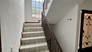 Una escalera con escalones de mármol y barandilla de metal, que conduce a una puerta con una cerradura decorativa.