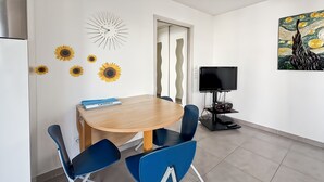 A modern room with a wooden dining table, blue chairs, a flat-screen TV, and a painting on the wall. - Modern 2 Bd Next To Rue D'antibes (Cannes)