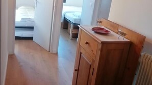 Un dormitorio con un aparador de madera, un plato rojo sobre el aparador y una cama con ropa blanca.