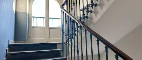 A staircase with dark wooden steps and black balusters, leading to a white door with a glass panel.