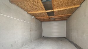 Et værelse med betongulv, træbjælker i loftet og en lukket rulleport.