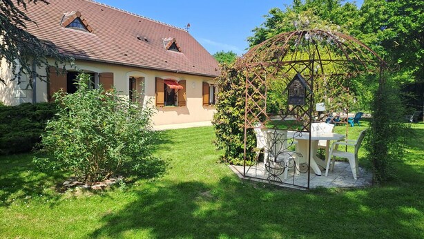 A house with a red-tiled roof, a garden with a pergola, and a table and chairs set up outside. - Family country house with garden, near Haras du Pin, peaceful and pleasant (Le Merlerault)