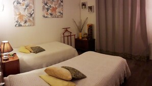 A hotel room with two beds, a nightstand, a lamp, and two wall-mounted paintings. - Family country house with garden, near Haras du Pin, peaceful and pleasant (Le Merlerault)
