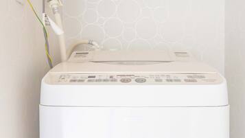 Eine weiße Waschmaschine in einem kleinen Raum mit einer Wand mit Muster.