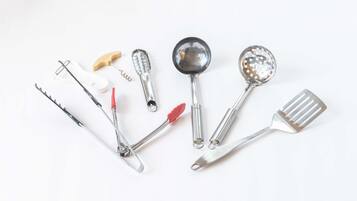 Un conjunto de utensilios de cocina, incluyendo un rallador, una cuchara, una espumadera y una espátula.
