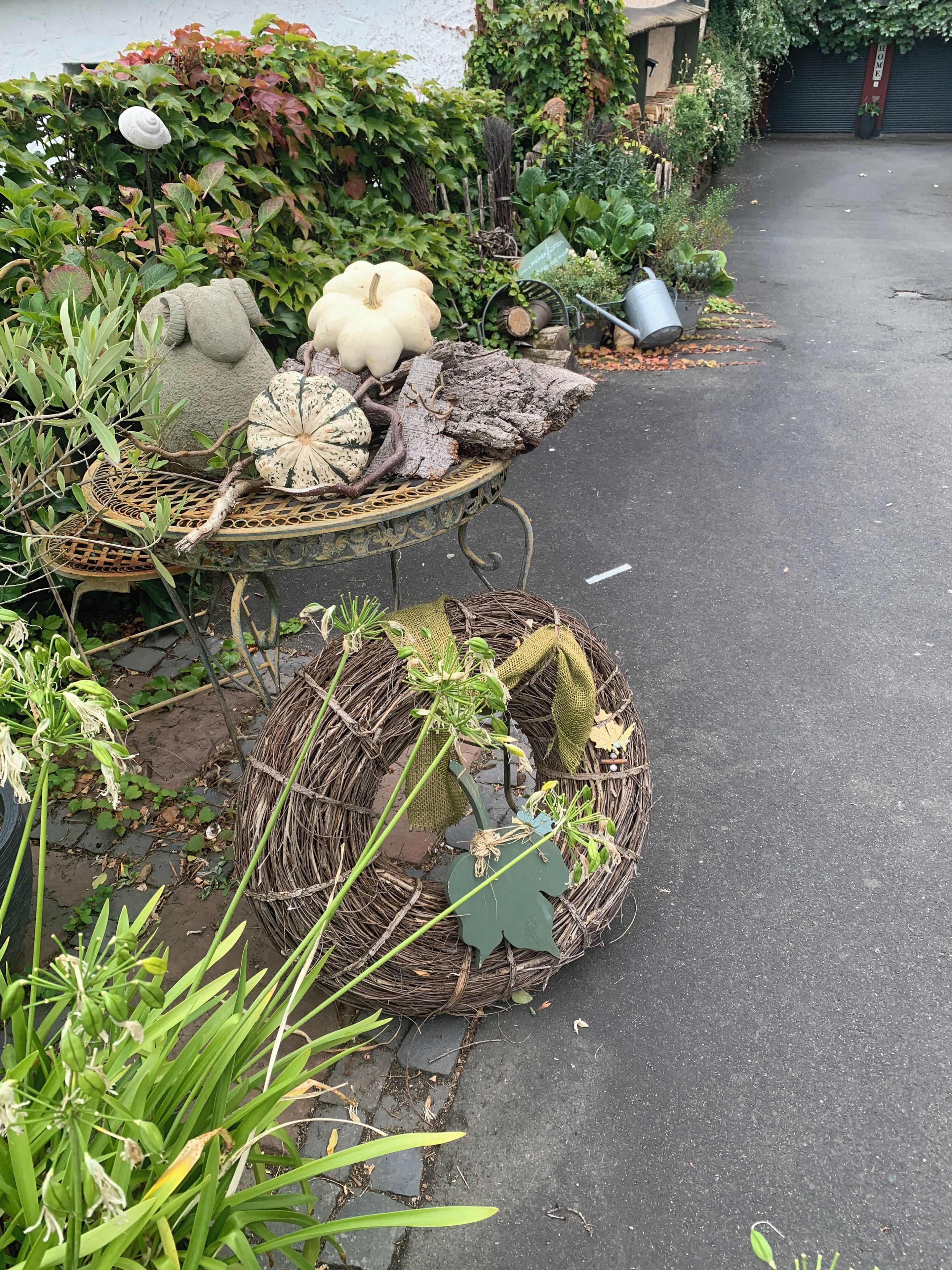 Ein Gartenweg mit dekorativen Pflanzgefäßen, die verschiedene Pflanzen enthalten, sowie ein Tisch mit einem gewebten Korb.
