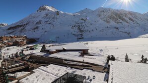 Een met sneeuw bedekte berg met een skigebied op de voorgrond, inclusief gebouwen en skipistes.