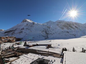 Une montagne enneigée, avec une station de ski au premier plan, comprenant des bâtiments et des pistes de ski.