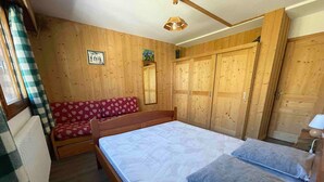 Een kamer met houten lambrisering, een bed, een bank en een kledingkast.