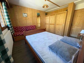 Une pièce aux murs lambrés, comprenant un lit, un canapé et une armoire.
