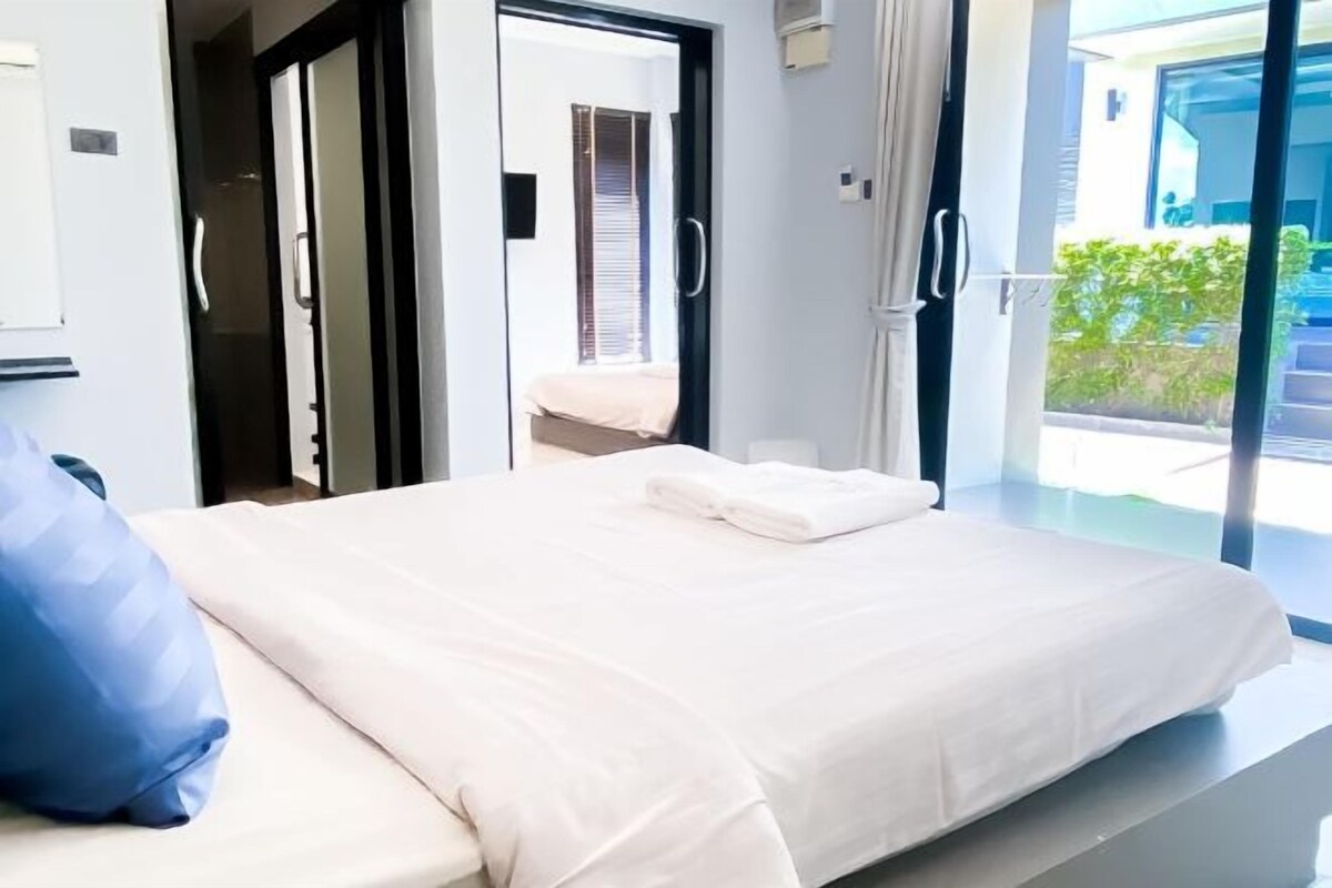 Une chambre moderne avec un grand lit, un oreiller bleu et une vue sur un balcon.