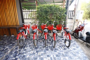 A row of red bicycles with baskets, parked on a tiled floor. - The Seacret Kohlarn (Koh Lan)
