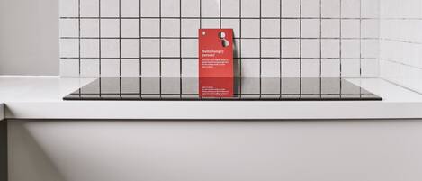 A red tag on a white tiled wall with a glass shelf below.