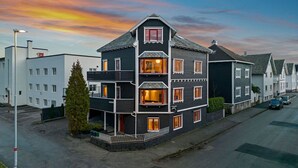 A multi-story residential building with a dark facade, multiple windows, and a balcony. - Staysville – City Center (Stavanger)