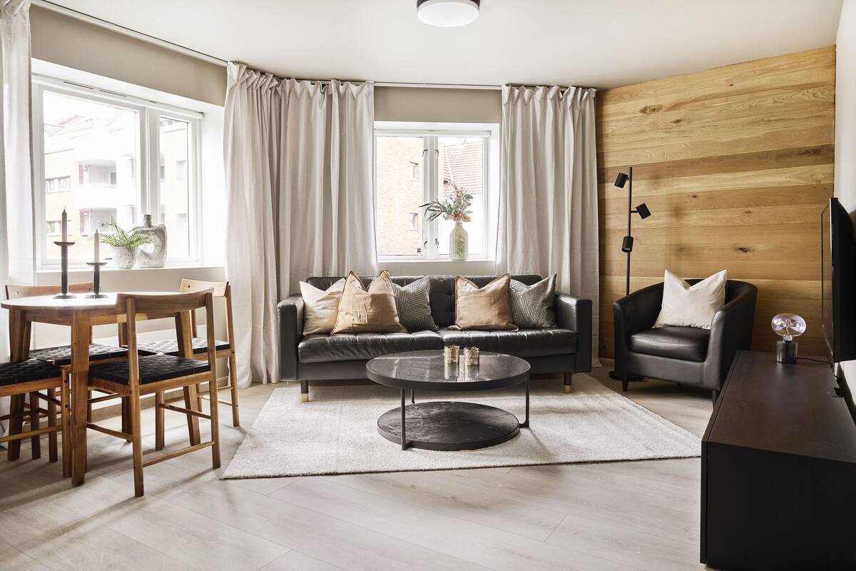 A modern living room with a sofa, a coffee table, a TV stand, and a dining area with a table and chairs.