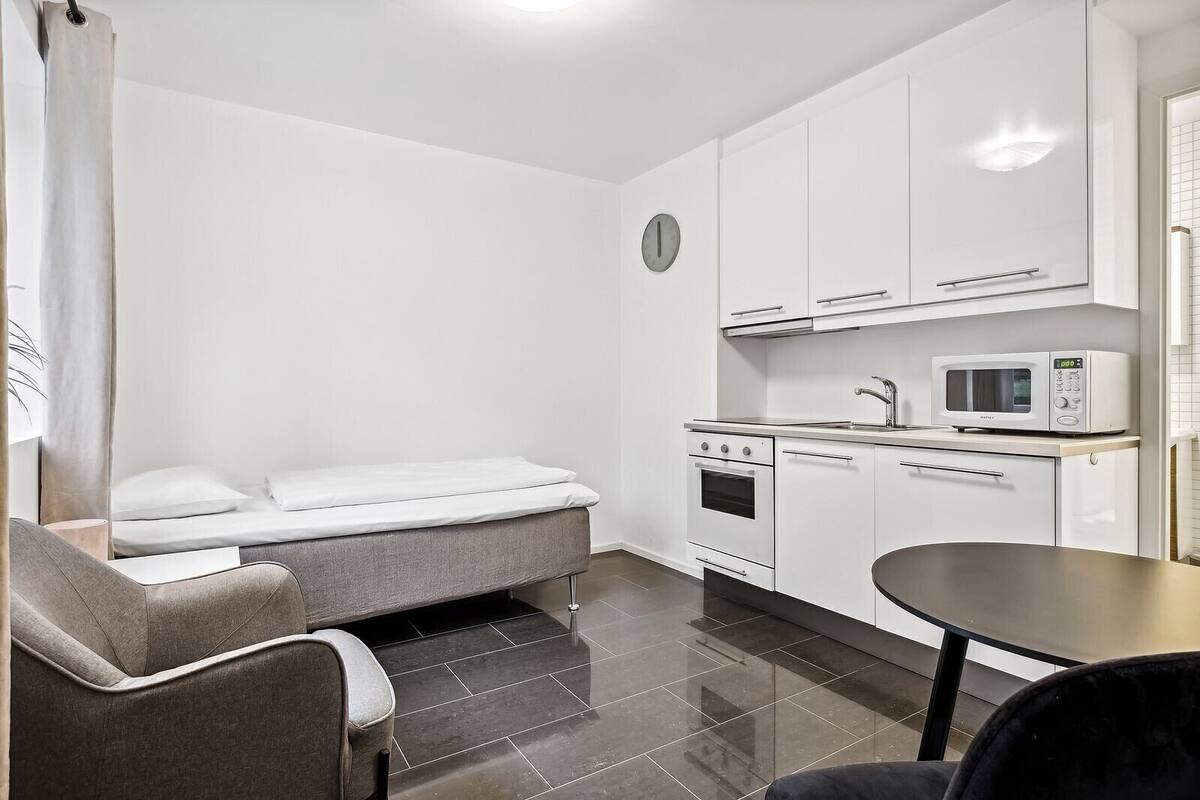 A compact kitchenette with a microwave, oven, and sink.