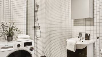 A modern bathroom with a washing machine, a sink, and a shower.