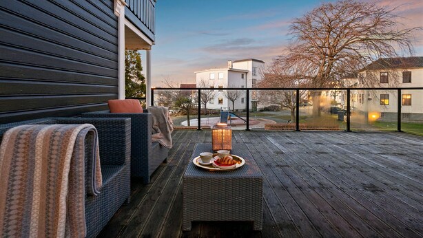 A wooden deck with outdoor furniture, a lantern, and a tray with food. - Staysville – City Center (Stavanger)