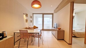 A modern hotel room with a dining area, a sofa, a TV, and a bed. - Suite La Giudecca (Gallipoli)