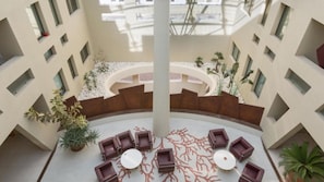 A spacious atrium with a central seating area, surrounded by walls with geometric cutouts and potted plants. - Suite La Giudecca (Gallipoli)