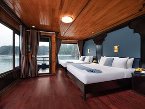 A cabin with two beds, wooden floors, and a view of the water. - La Pandora Boutique Cruise (Ha Long)