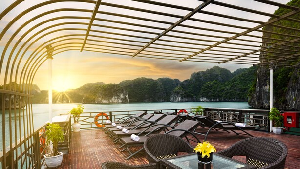 A covered outdoor seating area with wicker furniture, a glass table, and potted plants. - La Pandora Boutique Cruise (Tuan Chau)
