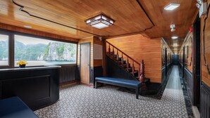 A wooden interior with a staircase, a bench, and a view of a mountainous landscape through a window. - La Pandora Boutique Cruise (Tuan Chau)
