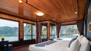 A spacious bedroom with a large bed, a wooden ceiling, and a view of a lake and mountains. - La Pandora Boutique Cruise (Tuan Chau)