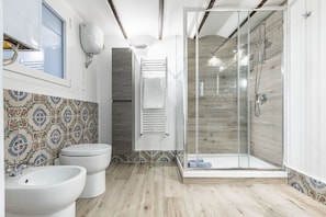 A bathroom with two sinks, a shower, and a toilet.