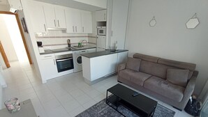 Een knus woongedeelte met een kitchenette, een bank en een salontafel.