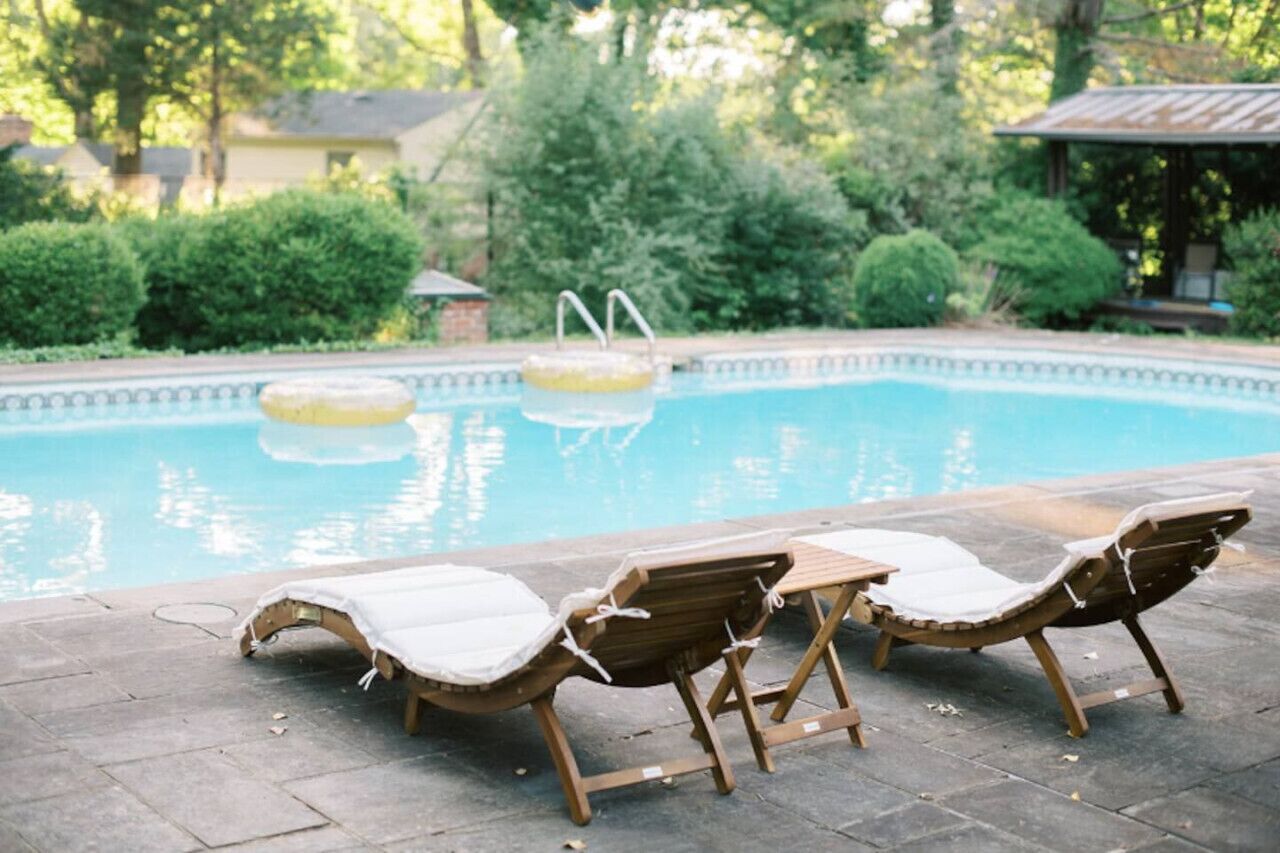 A swimming pool with lounge chairs and a small gazebo in the background.
