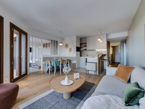 A modern living room with a round coffee table, a sofa, and a dining area with chairs. - 72m² Apartment, near slopes, 8 pax, parking, wifi (Montvalezan-La Rosière)
