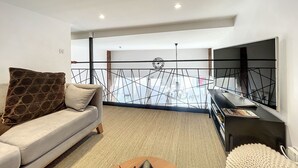 A modern living room with a sofa, a coffee table, and a TV. - Comfortable lodging in Saugues for hikers, 3 spacious rooms with en-suite bathroom (Saugues)