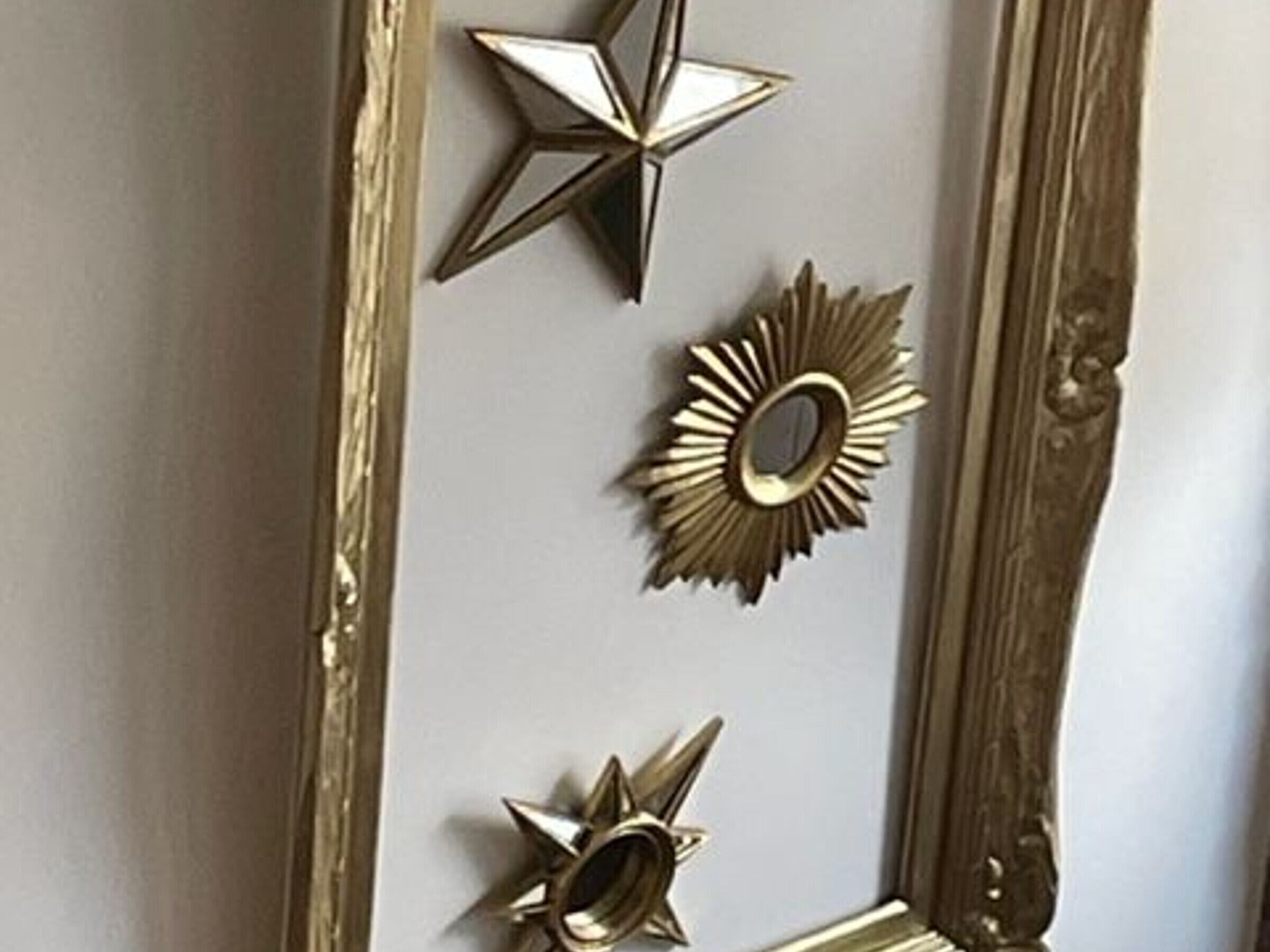 Une porte ornée d’un miroir décoratif et de trois éléments métalliques en forme d’étoile.