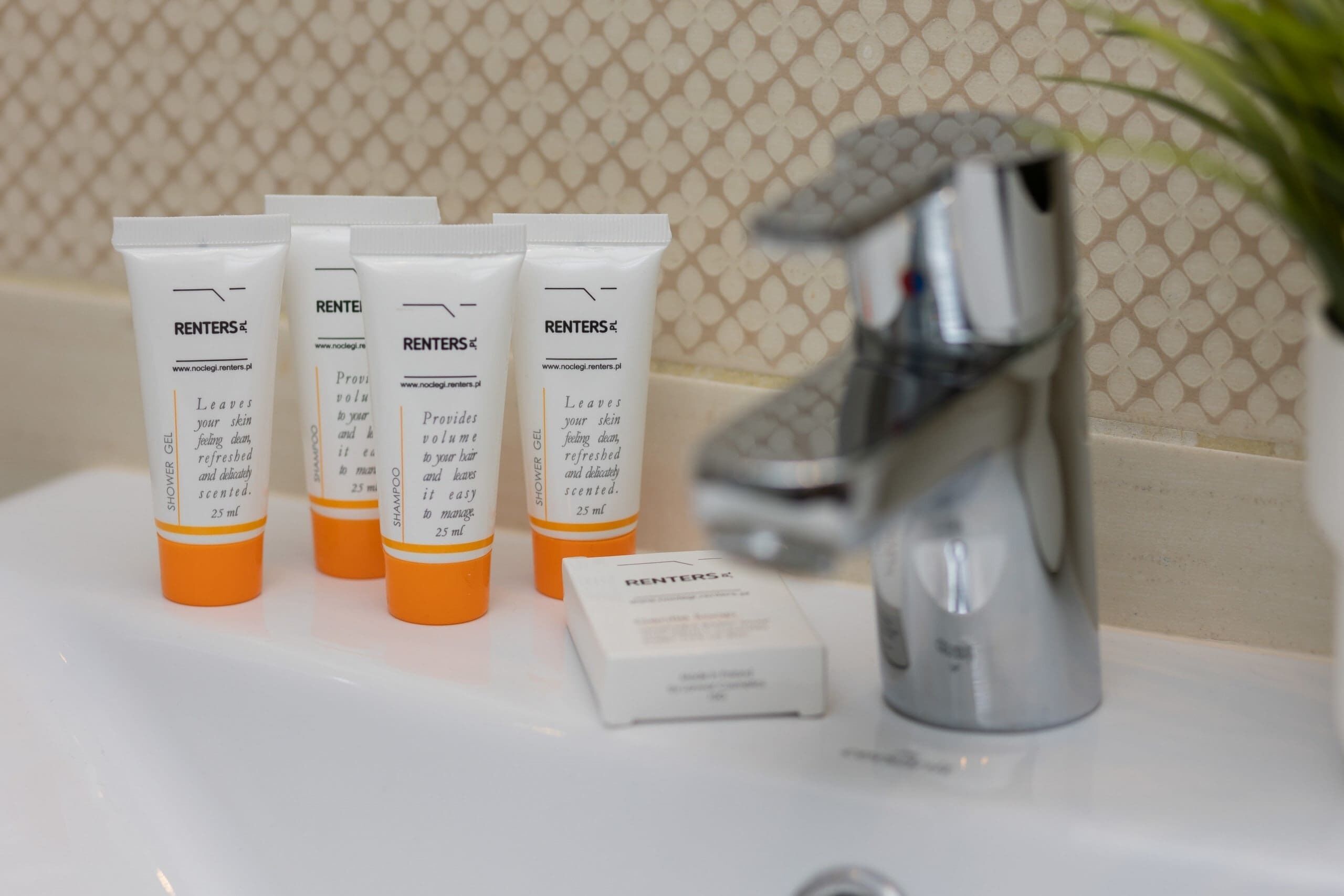 Un lavabo de salle de bain avec trois bouteilles de gel douche RENTERS® et un savon.