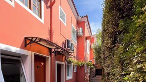 A narrow brick pathway flanked by buildings with red walls and white trim, leading to a door marked '01'. - GoodStay São Paulo Ibirapuera (São Paulo)